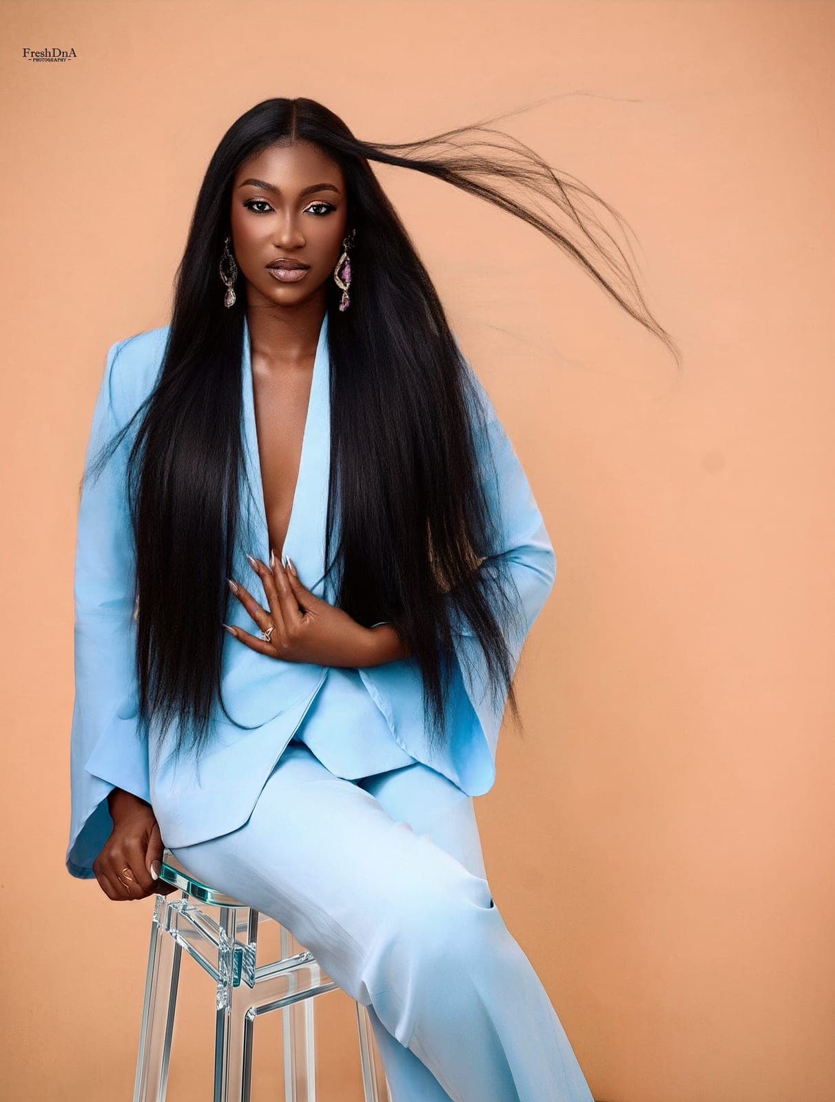 The sky-blue Moirai suit, jacket worn open, hair in motion